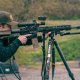 A man lining up his shot behind a scope and rifle.